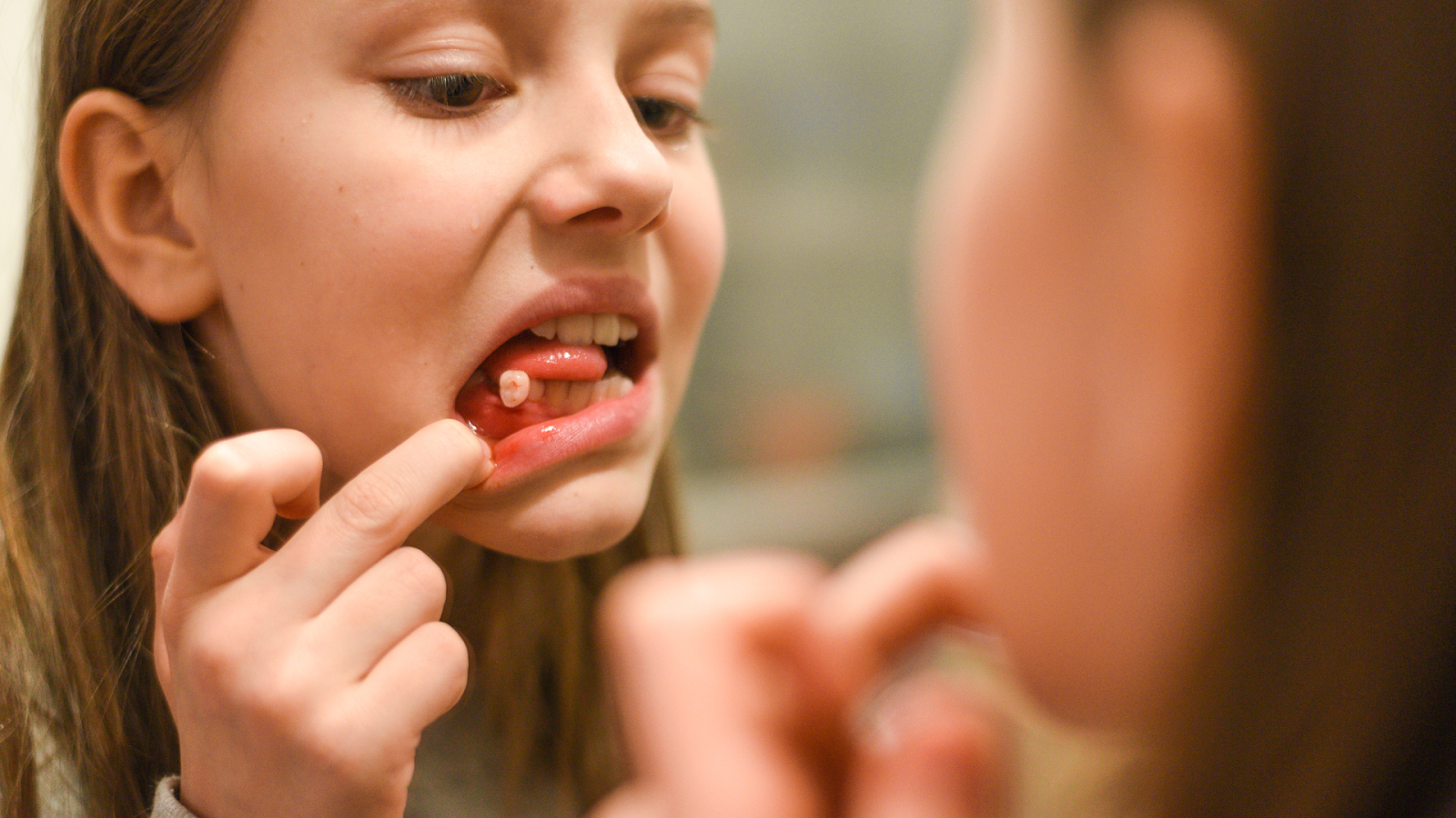 A young girl looking her teeth at Alfred Cheng Orthodontic Clinic, promoting good dental hygiene.